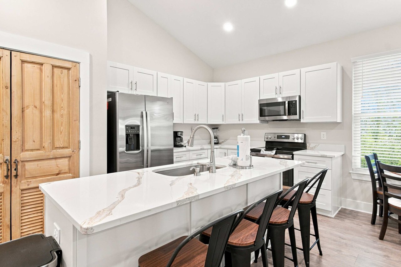 Gather around this bright, open kitchen with a spacious island perfect for meal prep or casual dining. Crisp white cabinetry and gleaming countertops invite you to cook up your favorite vacation recipes.