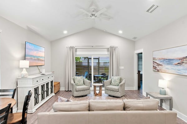 Step into your bright, airy living space with soaring vaulted ceilings and coastal charm. Plush seating invites you to unwind while doors open to your private patio for effortless indoor-outdoor living.